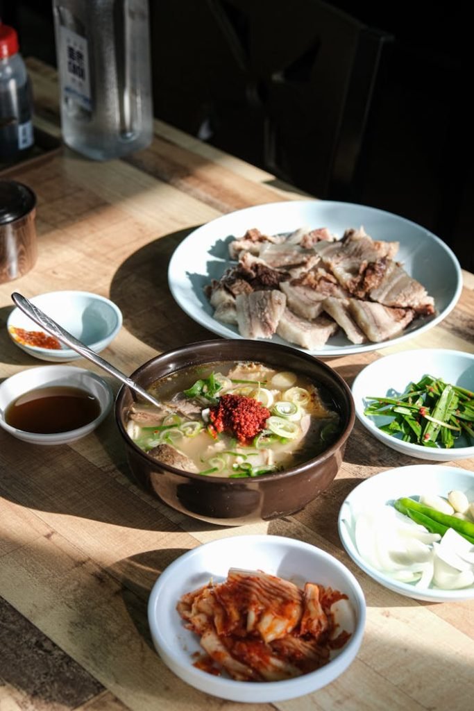 Delicious traditional Korean meal showcasing soup, meat, and side dishes on a wooden table.