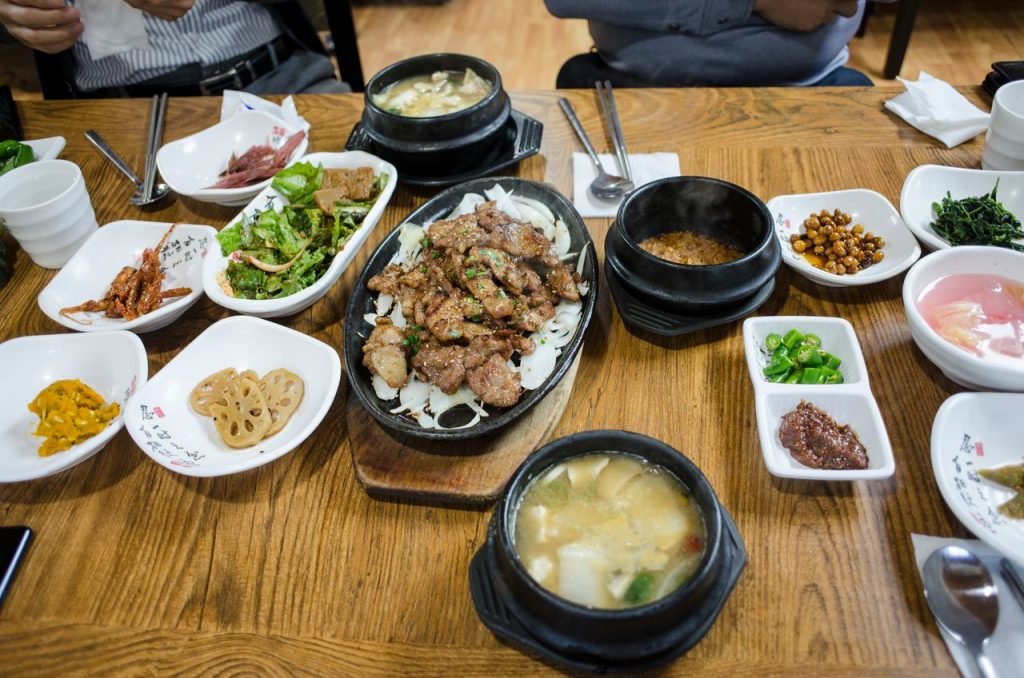 An overhead view of various Korean dishes served on a wooden table, showcasing traditional cuisine.