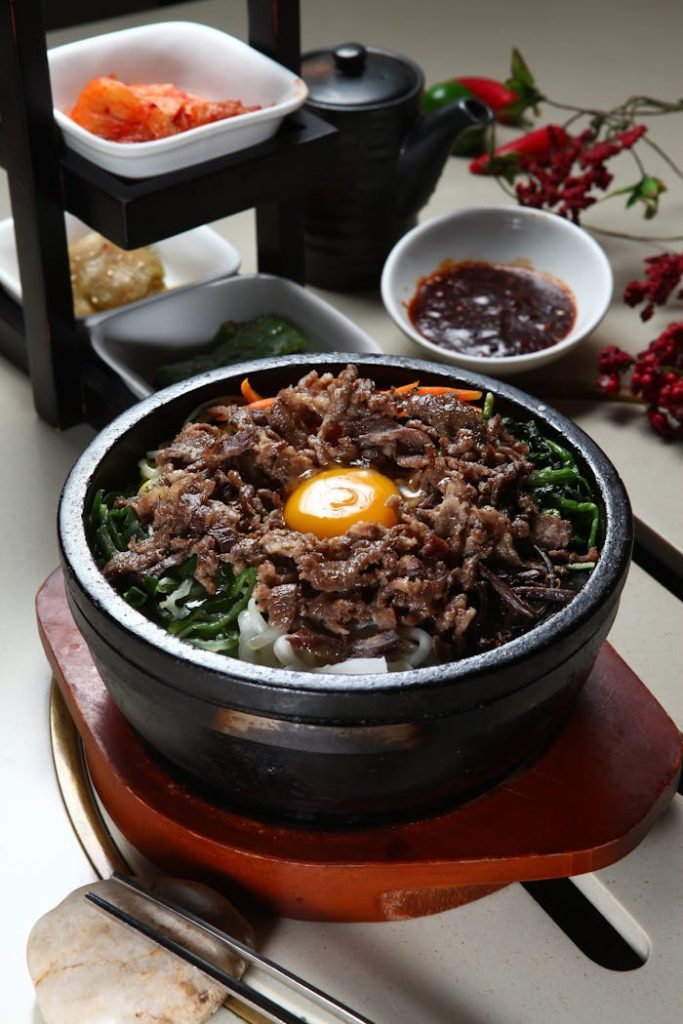 Authentic Korean bibimbap served in a stone pot with side dishes, showcasing traditional flavors.