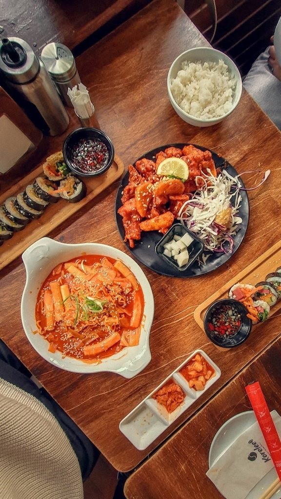 Korean food flat lay of Tteok-bokki, rabokki, kimchi, Korean fried chicken, kimbab